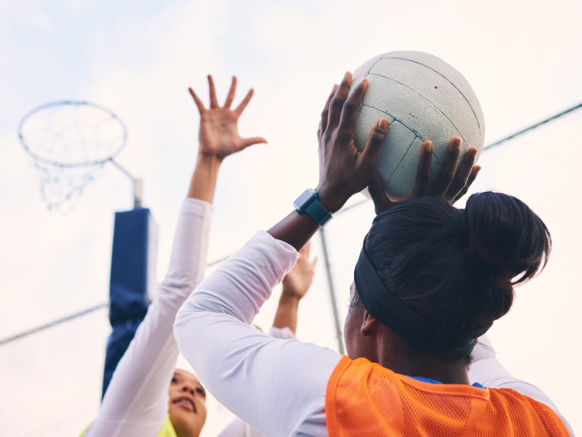 Netball, goal shooter and fitness of a girl athlete group on an outdoor sports court. Aim, sport ga.